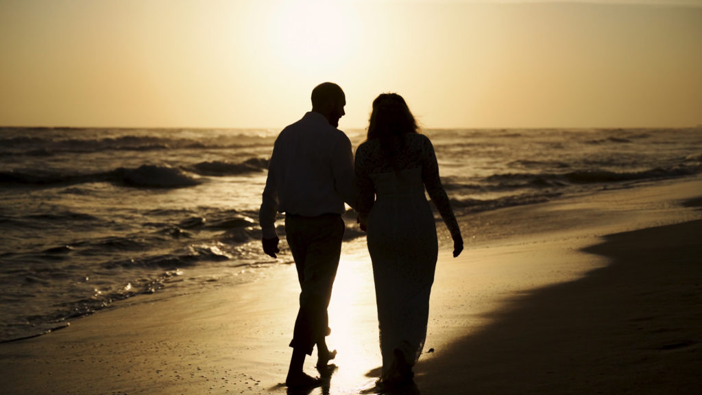 Couple walking along beach during Golden Hour.